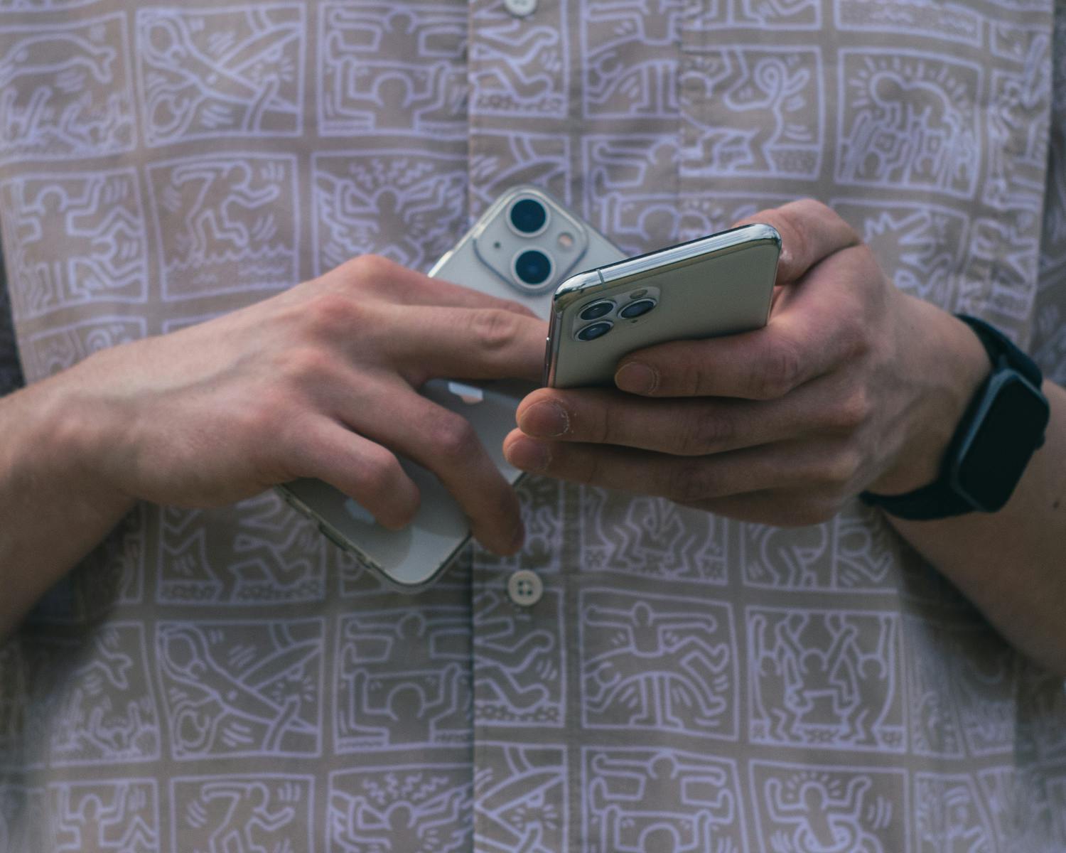 Detail of hands holding two smartphones, showcasing modern technology usage.