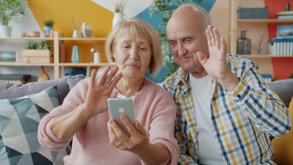 Elderly couple waving at smartphone screen