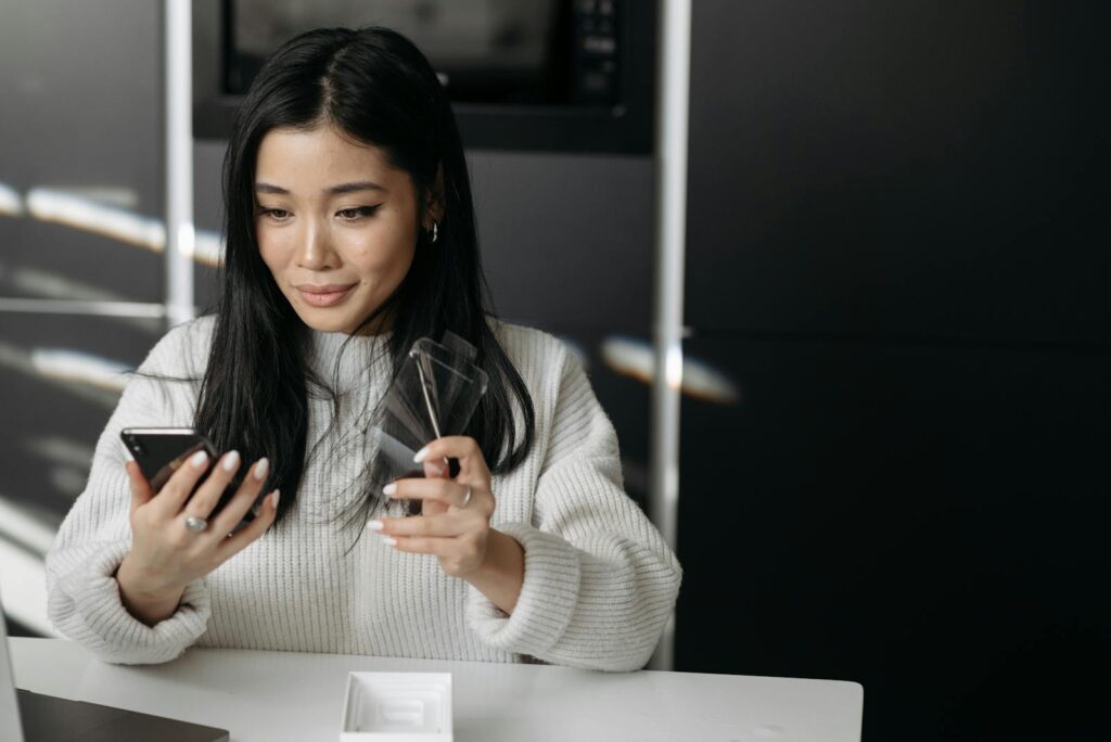 Woman unpacking and setting up a new smartphone device indoors.
