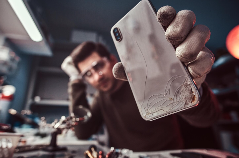 Cracked and worn-out smartphone being inspected, symbolizing the need to upgrade to a new phone.