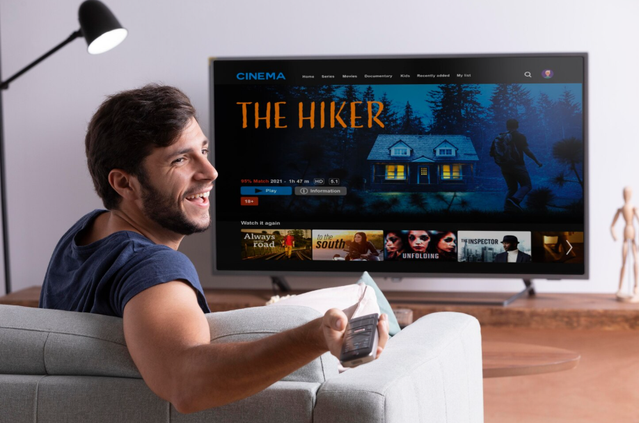 Man watching a movie on a smart TV at home while holding a remote